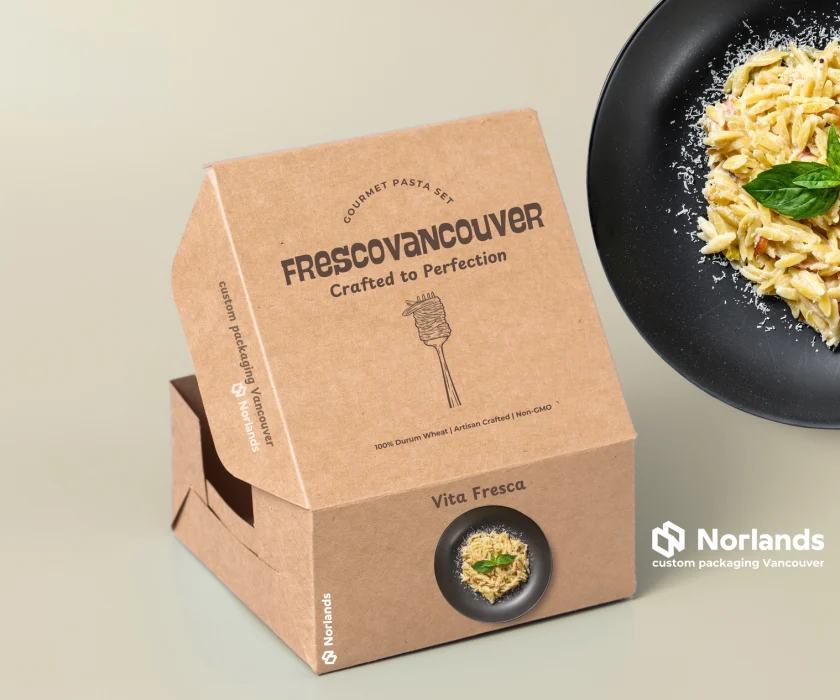 The image displays eco-friendly custom boxes for the food industry, designed by Norlands Custom Packaging Vancouver. The kraft packaging highlights simplicity and sustainability, featuring the tagline "Crafted to Perfection" and a minimalist illustration of pasta. A black plate with freshly cooked pasta garnished with basil and cheese complements the packaging, emphasizing the artisanal quality. This design showcases Norlands' expertise in creating high-quality custom printed boxes tailored for premium food products.