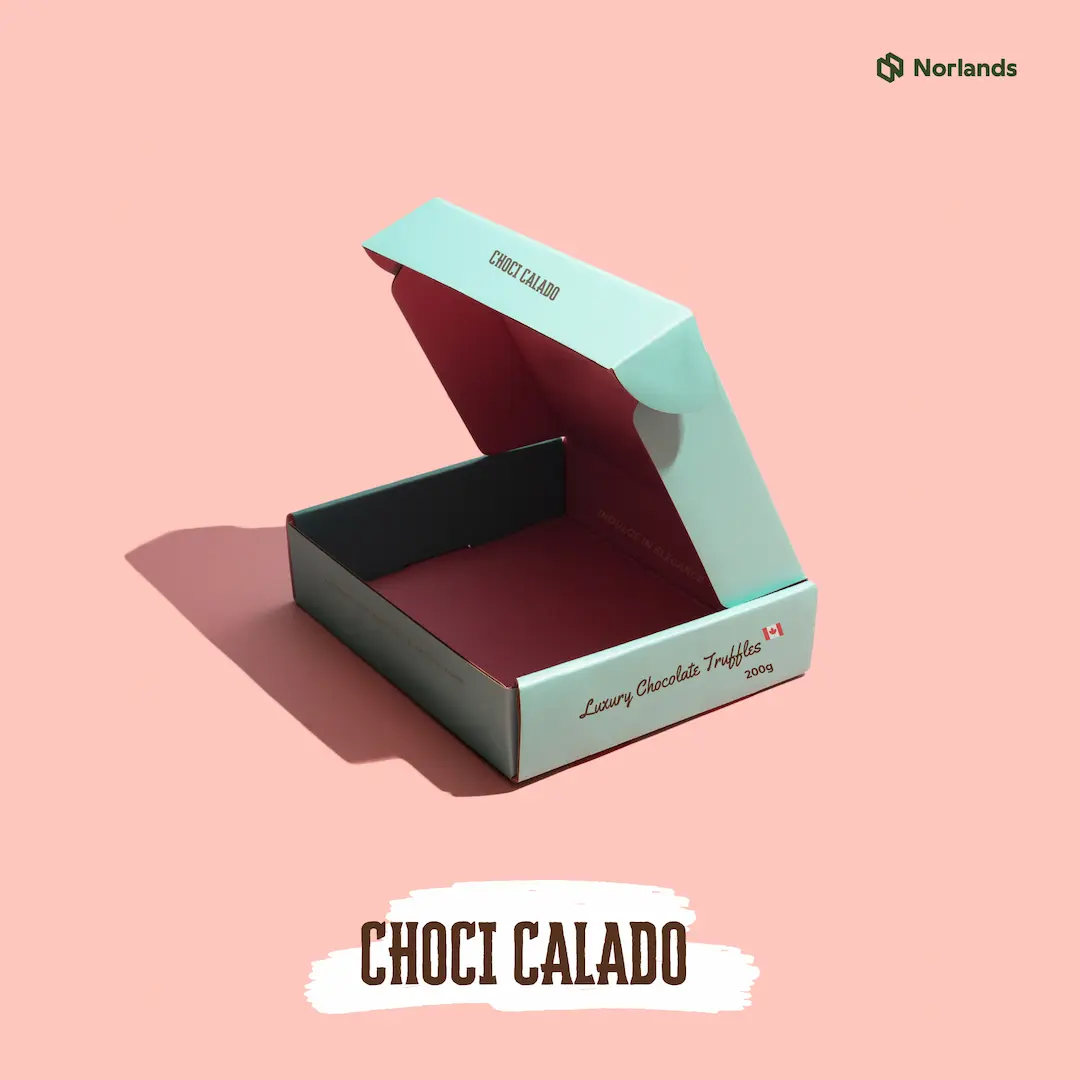 Elegant open box designed by Norlands for Choci Calado luxury chocolate truffles, featuring a soft pastel exterior and deep red interior, set against a pink background—showcasing premium, sustainable confectionery packaging.
