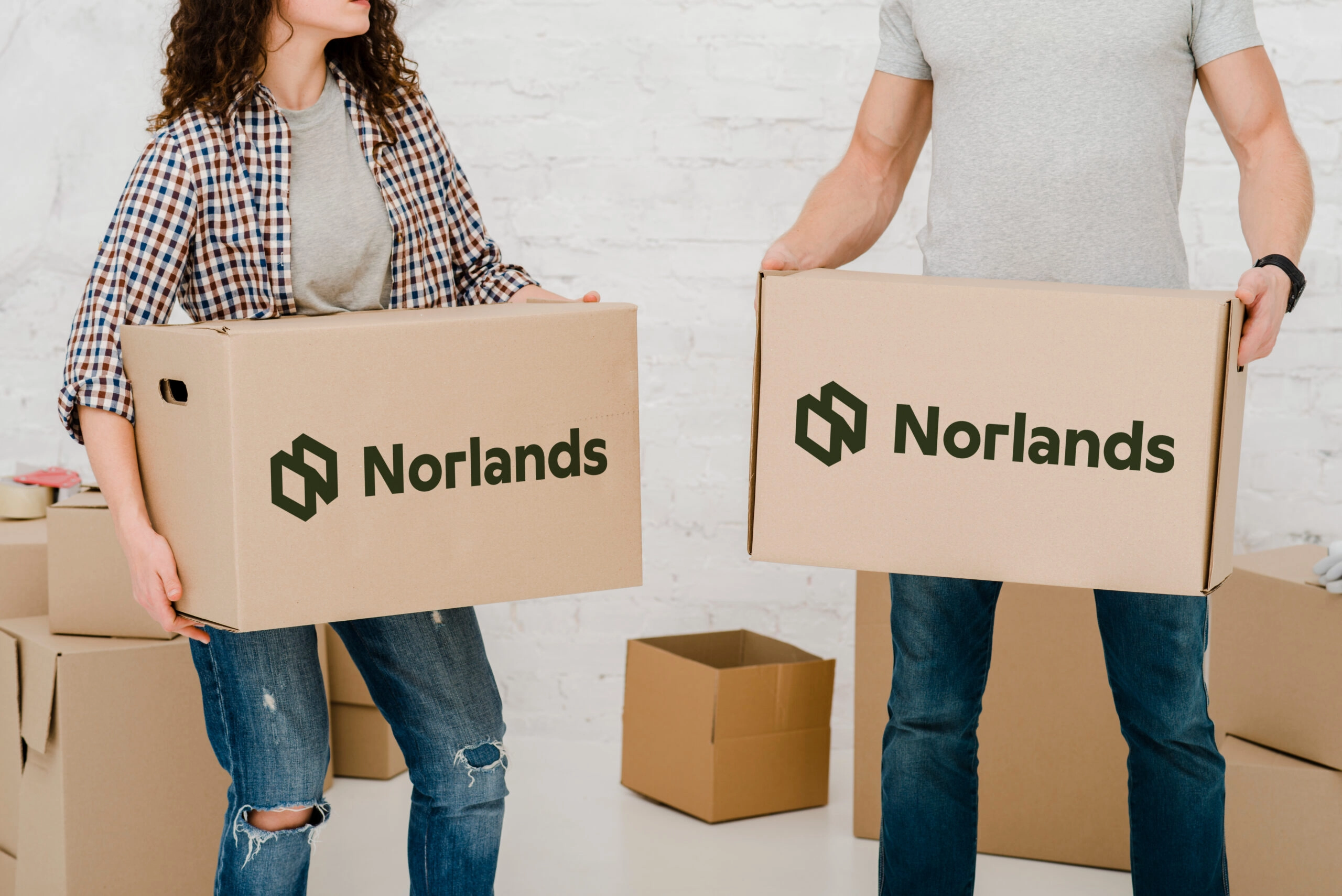 Two people holding Norlands branded cardboard boxes during a moving or packaging process.