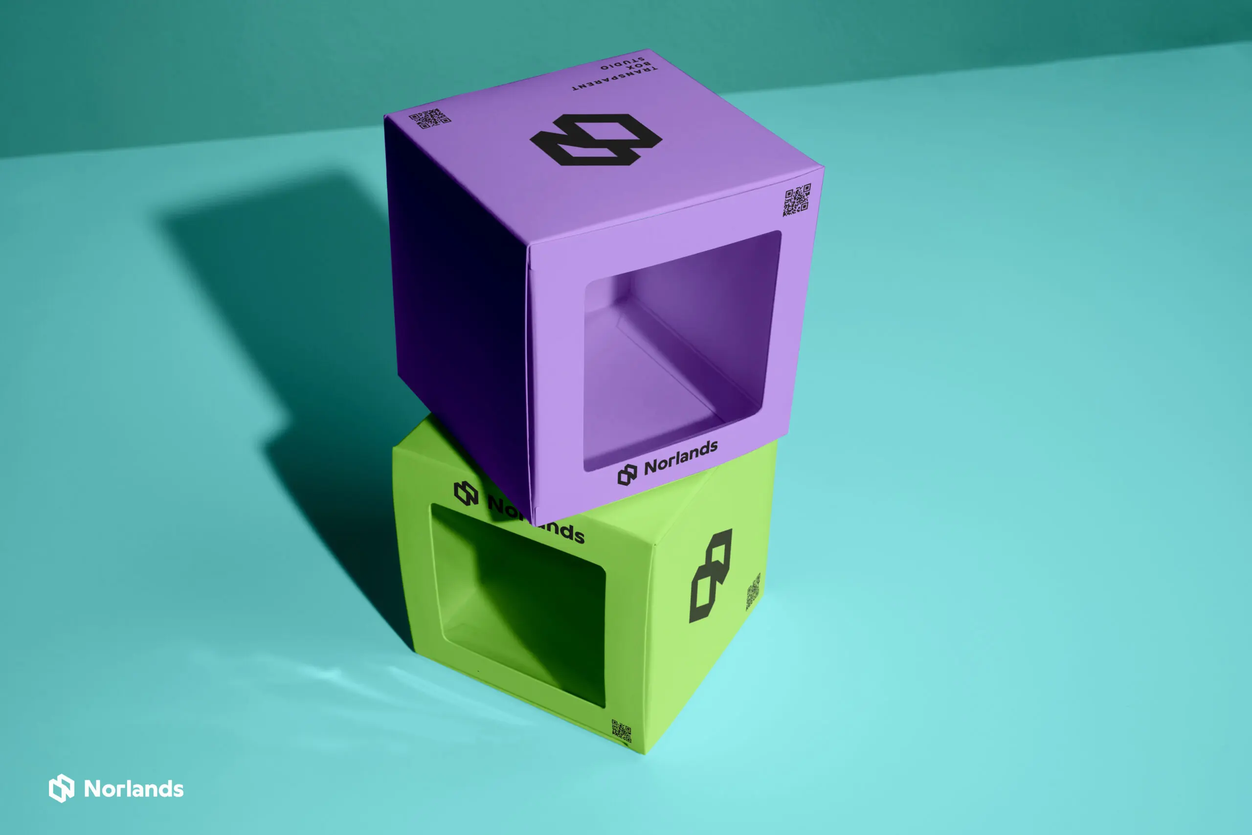 Two modern Norlands packaging boxes in bright purple and green with transparent display windows, stacked on a turquoise surface under studio lighting.
