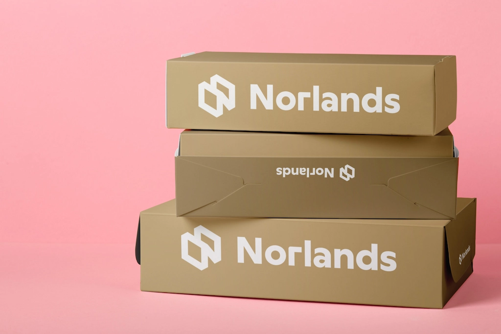 Stacked Norlands branded packaging boxes on a pink background, showcasing clean design and durable construction, representing premium custom cardboard boxes in Canada.