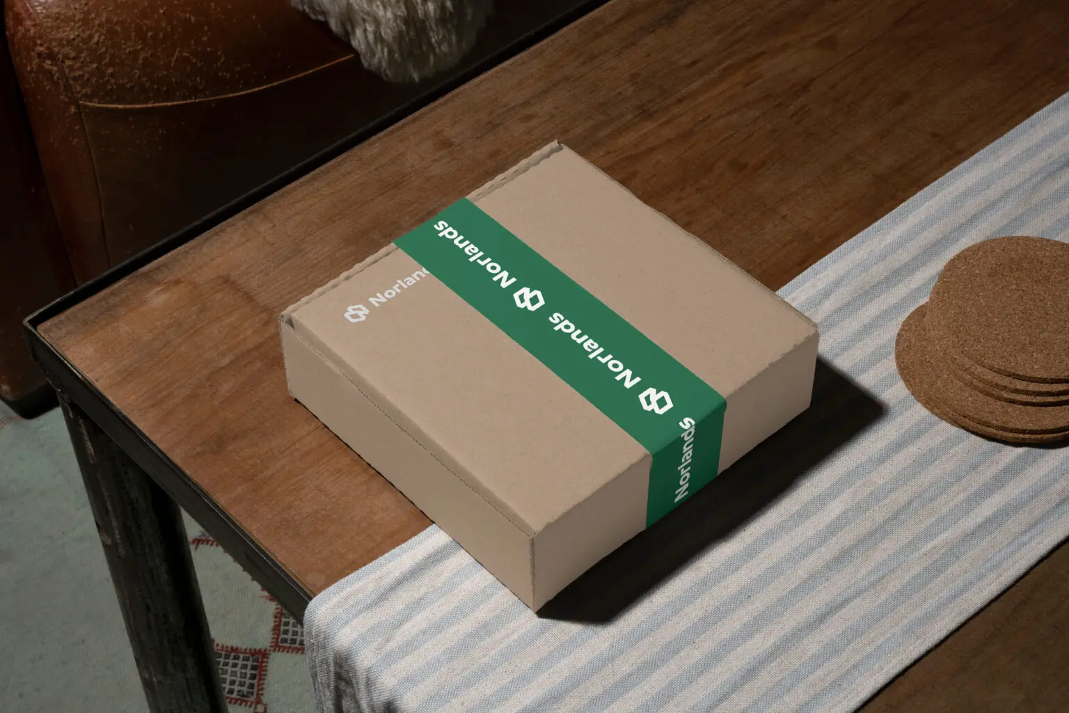 Norlands cardboard box with a green branded band placed on a wooden table with a striped cloth.