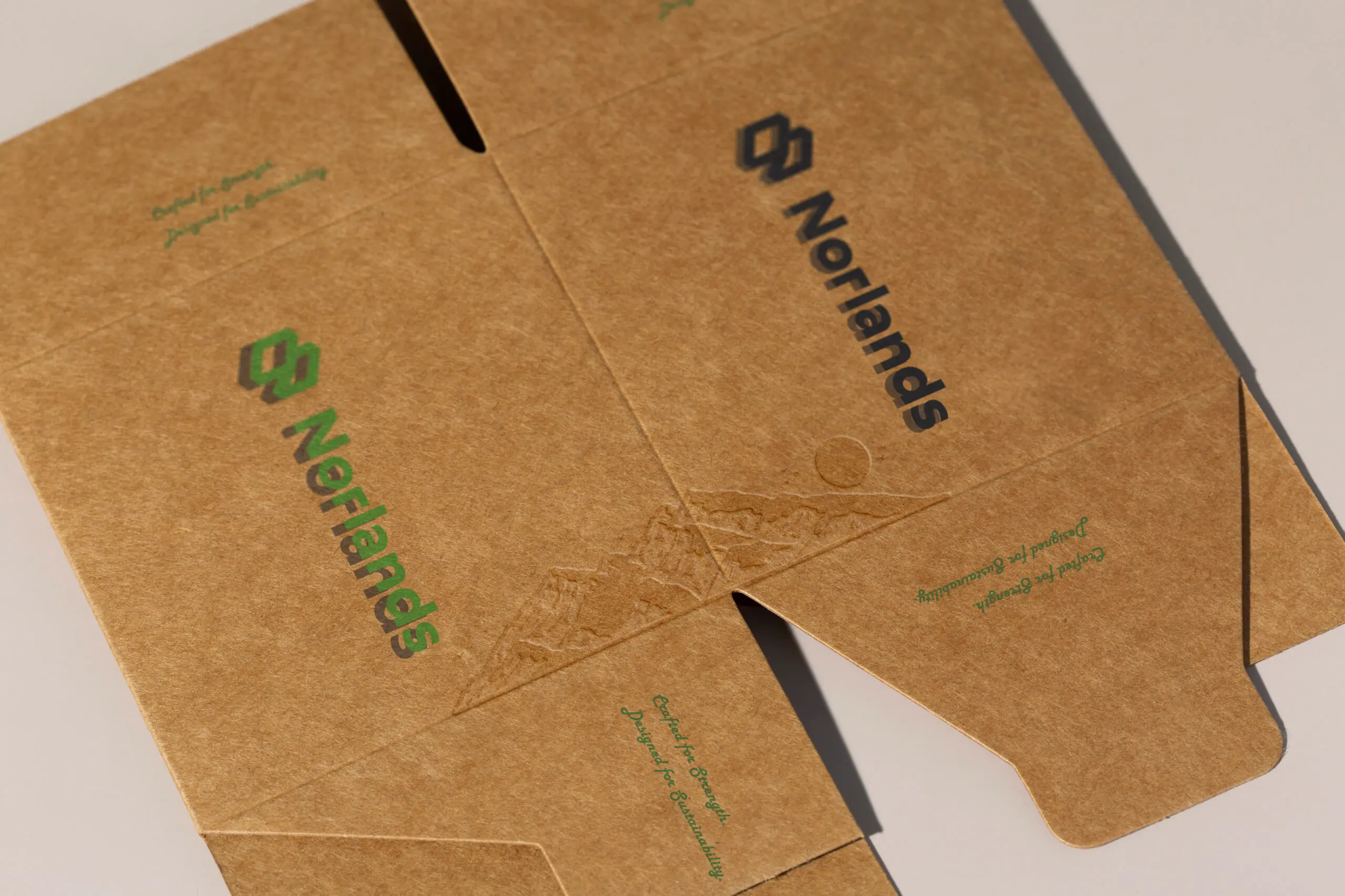 Flat brown kraft packaging sheets printed with the Norlands logo in green and black, prepared for folding into eco-friendly custom boxes.